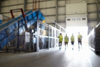 Four figures walking in an industrial interior, soft focus
